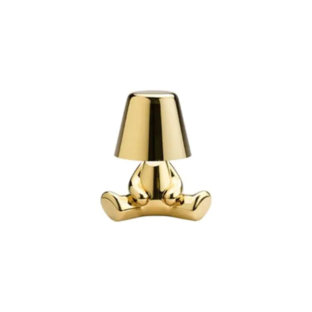 Gold LED table lamp shaped like a small man, providing a warm and inviting glow.