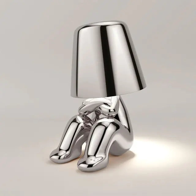 Silver LED table lamp in the shape of a small man, bringing a sense of whimsy to your space.