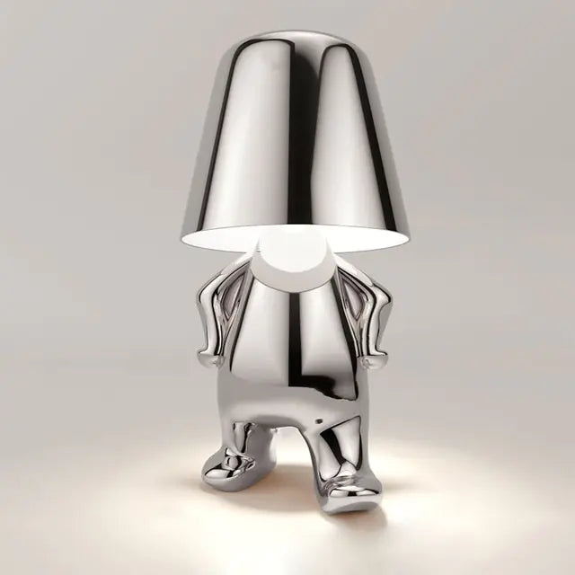 Silver LED table lamp shaped like a miniature man, adding a touch of personality to your room.