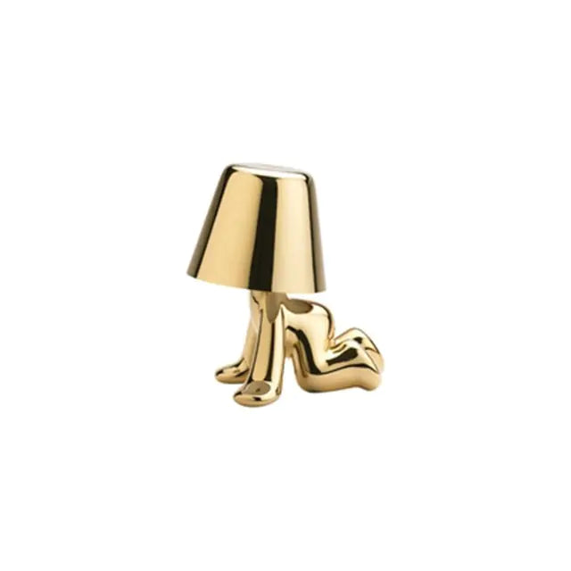 Gold table lamp designed as a small man figure, perfect for adding a touch of whimsy to your space.