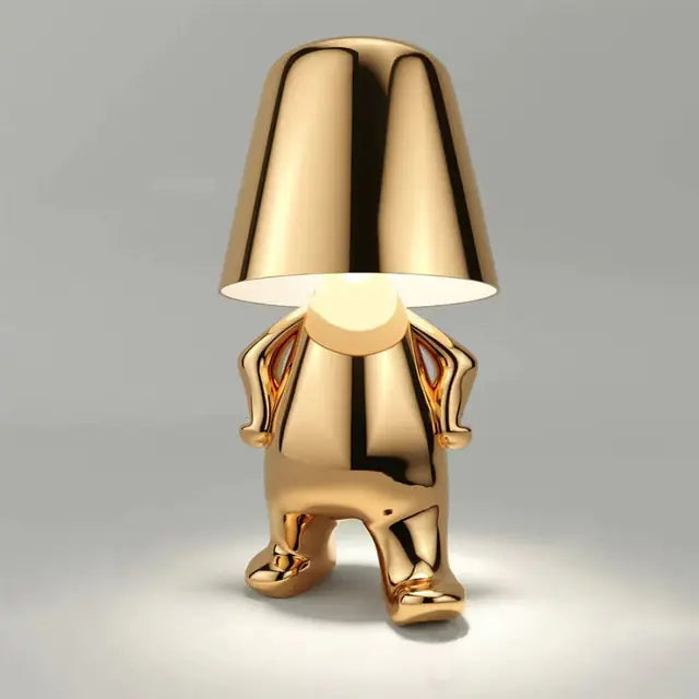 Gold table lamp with a small man figure design, ideal for adding character to any room.